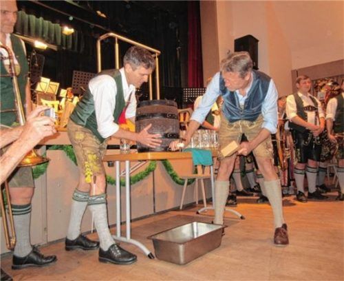 Bürgermeister und Musikmeister zapfen das Fass an.Foto re