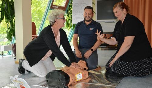 Der Defibrillator hat eine Sprachansage, den Bee-Gees-Song „Staying alive“ kennt die gehörlose Susanna Weber-Kühnlein (links) nicht. BRK-Ausbilder Mario Bicer nutzt eine Metronom-App, um ihr den richtigen Rhythmus – den der 70er-Jahre-Dance-Hit hätte – für die Herzdruckmassage zu zeigen. Gebärdensprachdolmetscherin Marie-Therese Gartner übersetzt und zeigt ihr mit den Händen, dass Susanna 30-mal im Takt auf den Brustkorb drücken soll.Foto Klemm