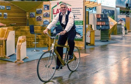 Nicht gerade ein klassisches Zimmererprodukt, aber gerade deshalb ein Beispiel für die Innovationskraft des Handwerks: Franz Wörndl von der Rosenheimer Zimmererinnung auf einem Fahrrad mit Holzrahmen, das einer seiner Mitarbeiter fertigte.